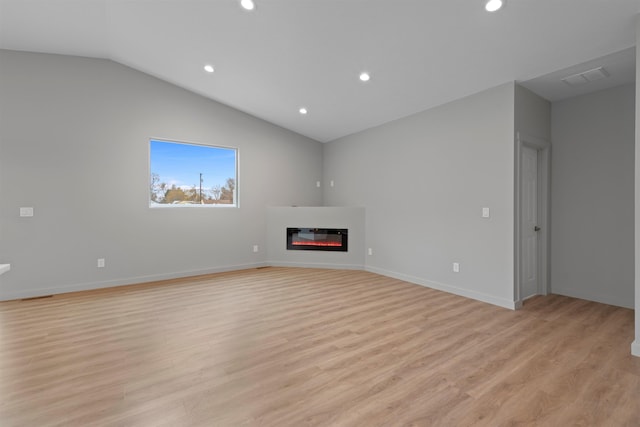 unfurnished living room featuring light wood-type flooring, recessed lighting, vaulted ceiling, and a glass covered fireplace