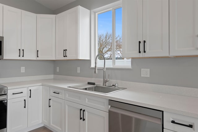 kitchen with a sink, white cabinets, light countertops, and stainless steel dishwasher