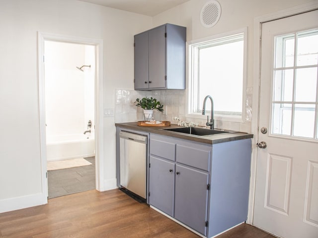 kitchen with a sink, tasteful backsplash, dishwasher, and wood finished floors