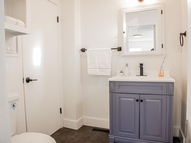 bathroom with toilet, vanity, and baseboards