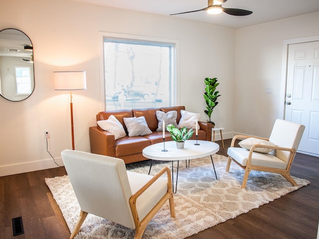 living room with a ceiling fan, baseboards, and dark wood-type flooring