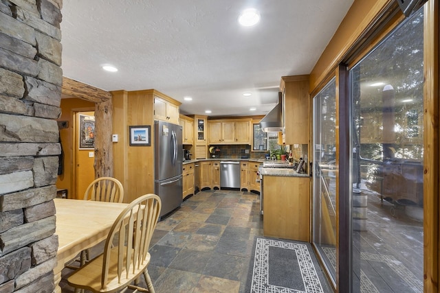 kitchen with decorative backsplash, stone finish floor, range hood, stainless steel appliances, and recessed lighting