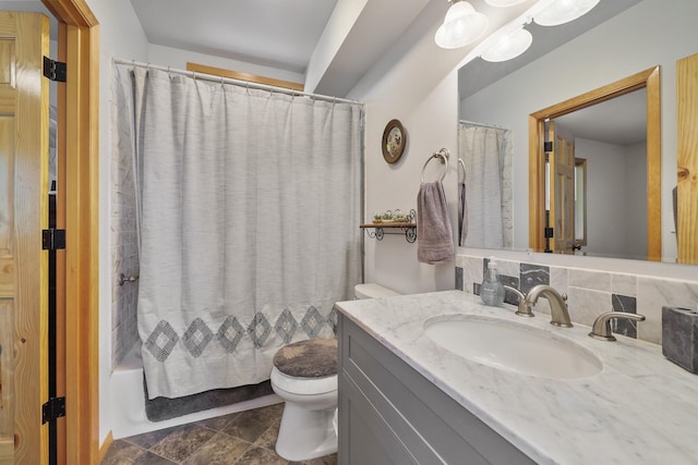 full bath featuring shower / bath combination with curtain, stone finish floor, vanity, and toilet