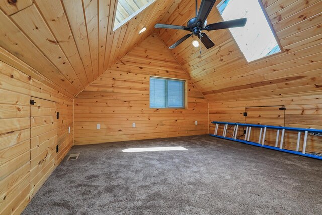 additional living space featuring carpet floors, vaulted ceiling with skylight, wood ceiling, and wood walls