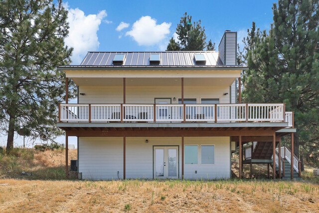 back of house featuring metal roof, stairs, french doors, a wooden deck, and a chimney