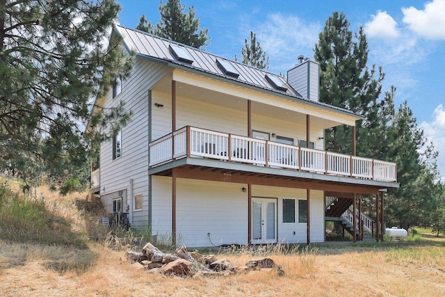 exterior space with a standing seam roof, metal roof, a chimney, and a wooden deck