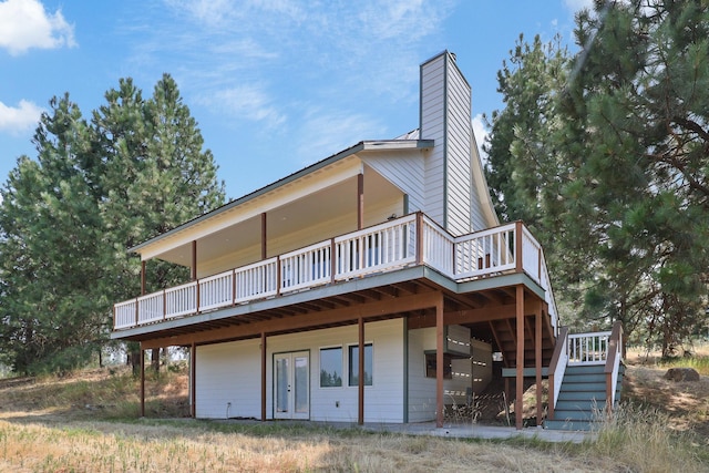 rear view of property featuring stairs, a chimney, and a wooden deck