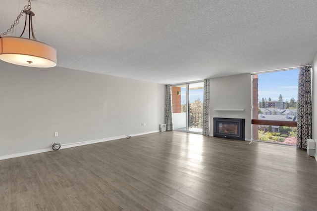 1311 S Westcliff Pl Unit 509, Spokane, WA 99224 - unfurnished living room featuring a textured ceiling, a wall of windows, a glass covered fireplace, plenty of natural light, and wood finished floors