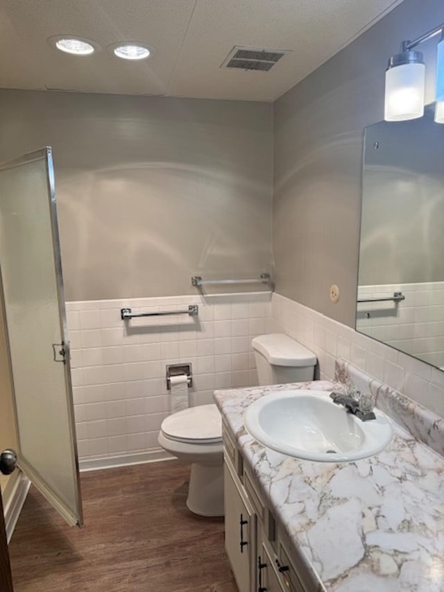 bathroom with visible vents, a wainscoted wall, toilet, wood finished floors, and vanity