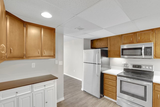1311 S Westcliff Pl Unit 509, Spokane, WA 99224 - kitchen with appliances with stainless steel finishes, light wood finished floors, baseboards, brown cabinets, and a drop ceiling