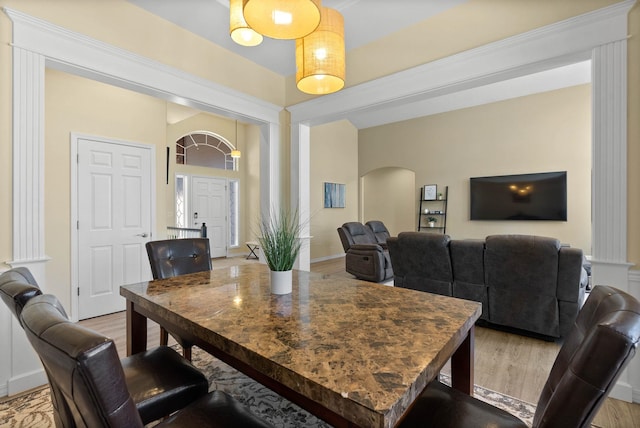 dining space with arched walkways, light wood-type flooring, and baseboards