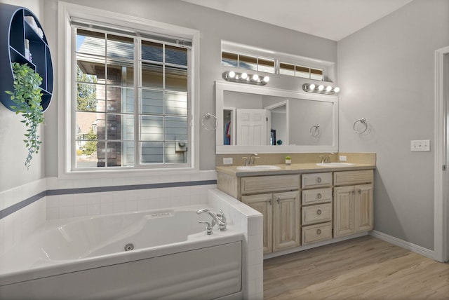 full bathroom featuring a whirlpool tub, double vanity, a sink, and wood finished floors