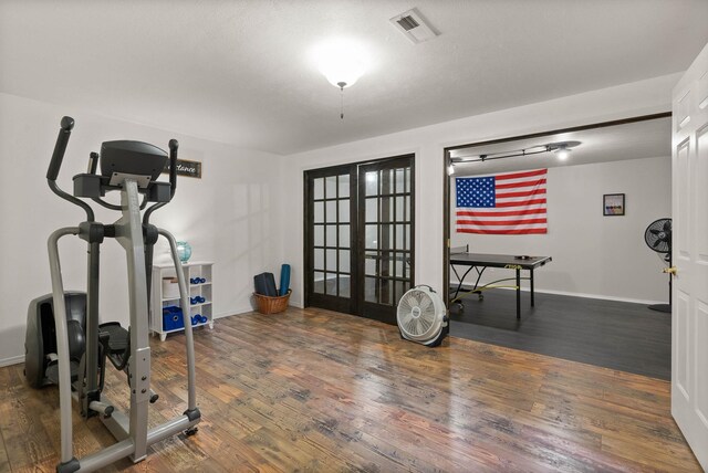 exercise room with french doors, wood finished floors, visible vents, and baseboards