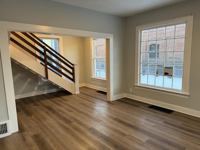 interior space with stairs, dark wood-style floors, visible vents, and baseboards