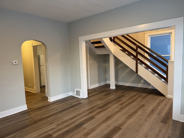 interior space with arched walkways, visible vents, baseboards, and wood finished floors