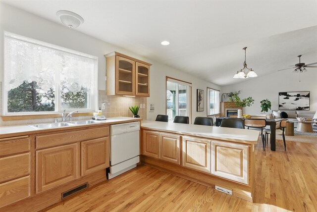 kitchen with light countertops, visible vents, a sink, dishwasher, and a peninsula