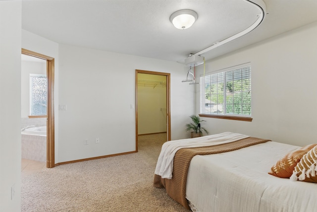 bedroom featuring baseboards, ensuite bathroom, carpet, a walk in closet, and a closet