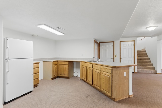 kitchen featuring light carpet, light countertops, a sink, and freestanding refrigerator