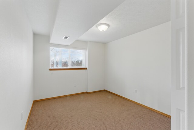 spare room with baseboards, visible vents, and light colored carpet