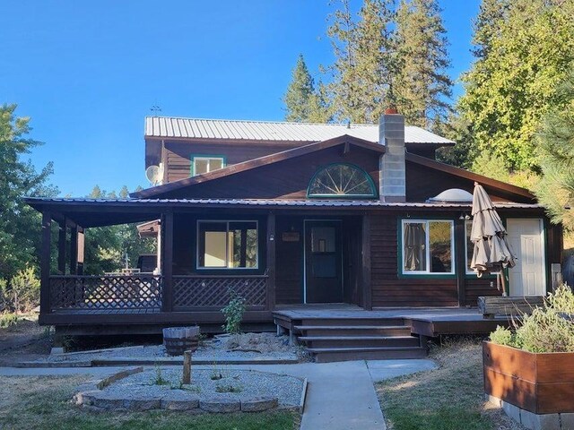 view of front of property featuring covered porch, metal roof, and a chimney