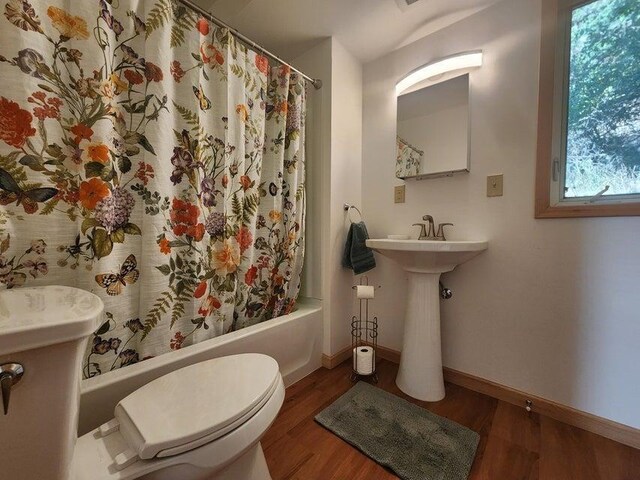 full bathroom with shower / bath combination with curtain, wood finished floors, toilet, and baseboards