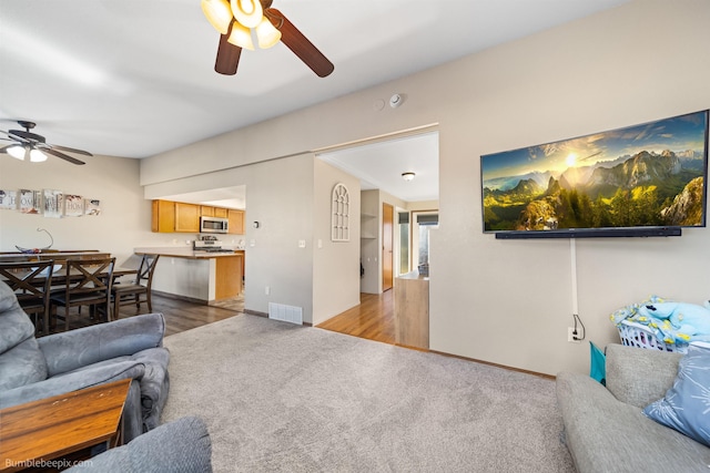 carpeted living room with ceiling fan, visible vents, and baseboards