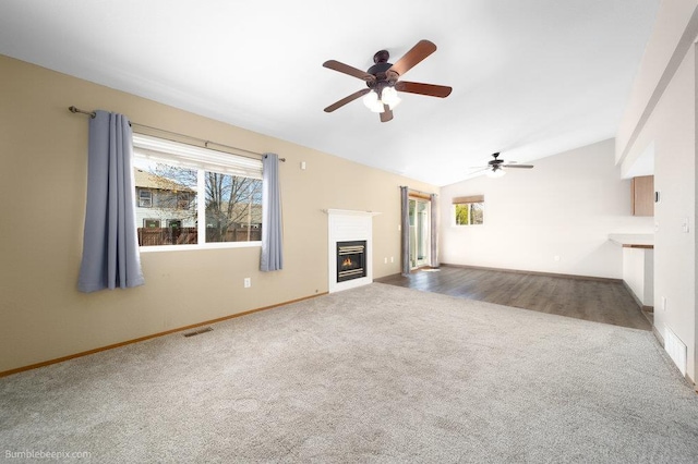 510 N Bell St, Spokane Valley, WA 99016 - unfurnished living room with vaulted ceiling, a glass covered fireplace, visible vents, carpet, and ceiling fan