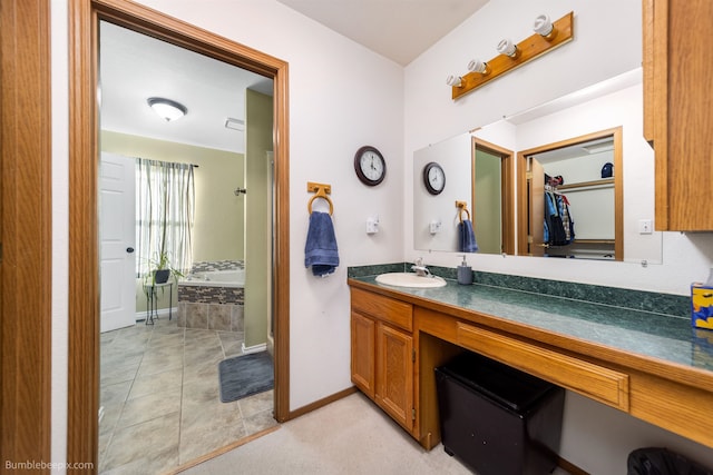 bathroom featuring a garden tub, vanity, baseboards, and tile patterned floors