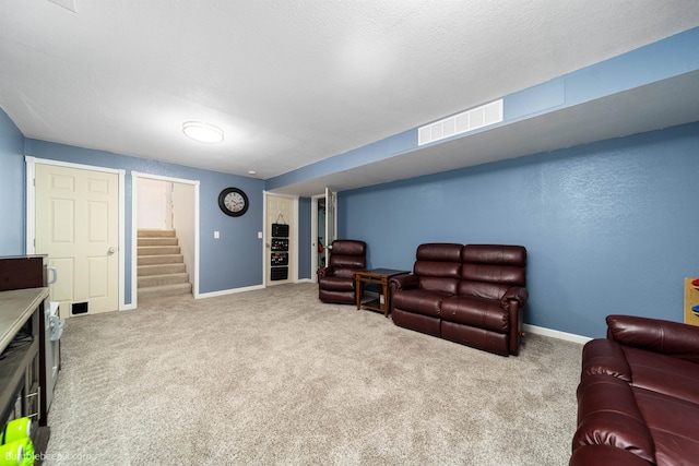 carpeted living area with stairway, baseboards, visible vents, and a textured ceiling