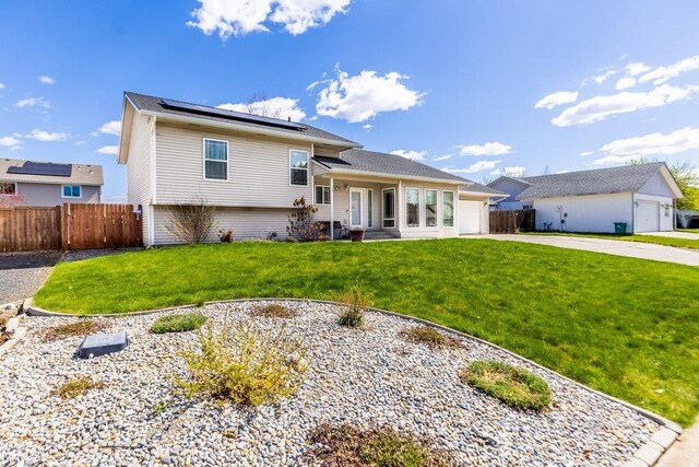 510 N Bell St, Spokane Valley, WA 99016 - view of front of property featuring a front lawn, driveway, roof mounted solar panels, fence, and an attached garage