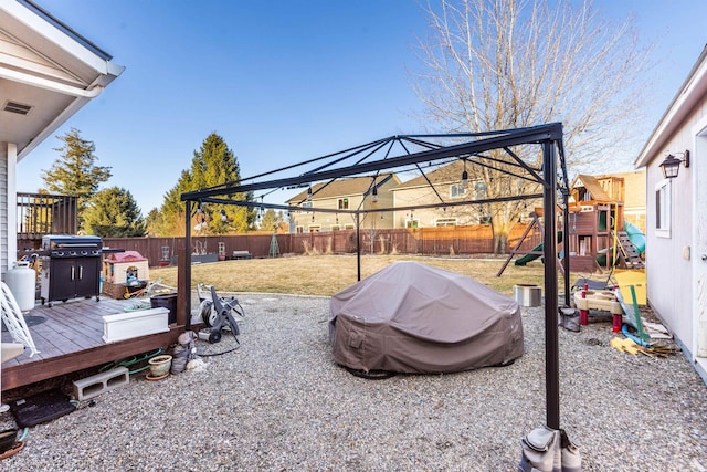 view of yard with a fenced backyard, a deck, and a playground