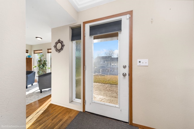 doorway featuring baseboards and wood finished floors