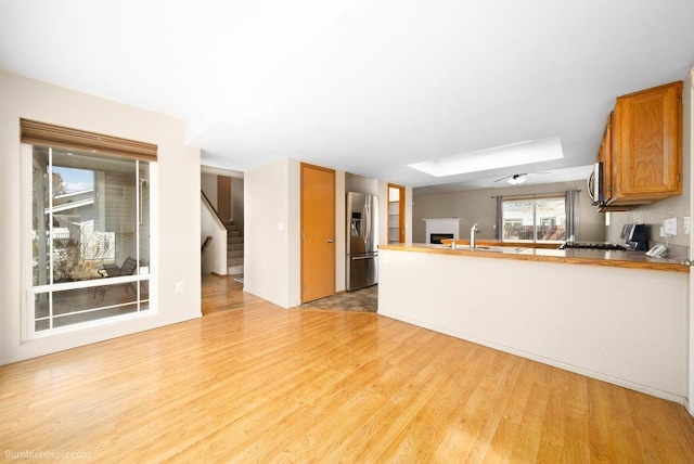 510 N Bell St, Spokane Valley, WA 99016 - interior space featuring light wood finished floors, stainless steel appliances, a peninsula, and brown cabinets