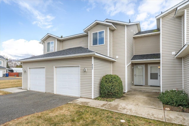 view of front facade featuring aphalt driveway, an attached garage, and a shingled roof