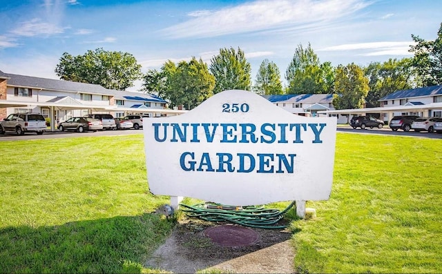 community / neighborhood sign with covered parking, a residential view, and a lawn