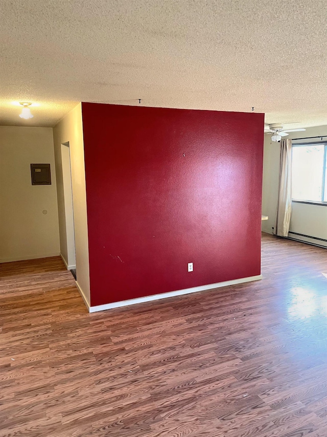 spare room with a textured ceiling, wood finished floors, and baseboards