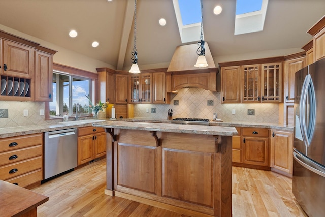 kitchen with a kitchen breakfast bar, stainless steel appliances, vaulted ceiling with skylight, and brown cabinets