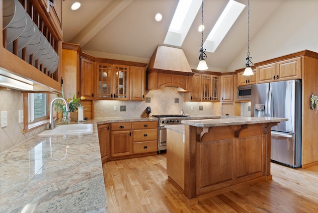 kitchen featuring a skylight, light stone counters, stainless steel appliances, and a sink