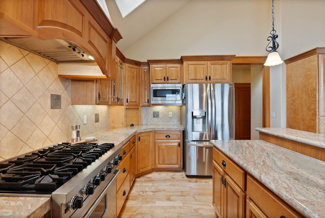 kitchen with light wood finished floors, light stone counters, decorative light fixtures, custom exhaust hood, and stainless steel appliances