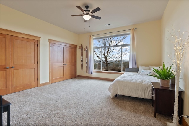 carpeted bedroom featuring a ceiling fan, visible vents, and baseboards