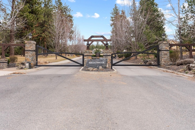 view of street featuring a gate, a gated entry, and curbs