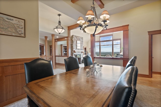 dining area featuring an inviting chandelier, decorative columns, light wood-style flooring, and beam ceiling