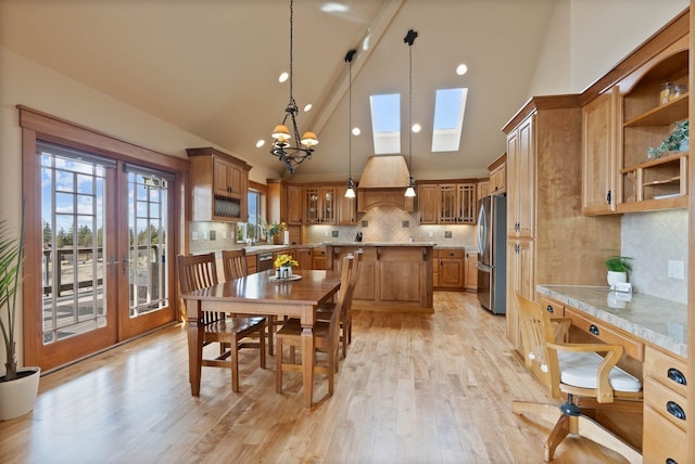 dining space featuring light wood-style floors, a skylight, high vaulted ceiling, and french doors