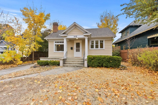 bungalow-style home with a chimney and fence