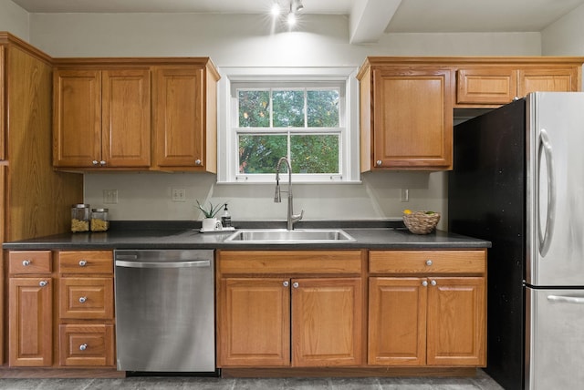 kitchen featuring appliances with stainless steel finishes, brown cabinetry, dark countertops, and a sink