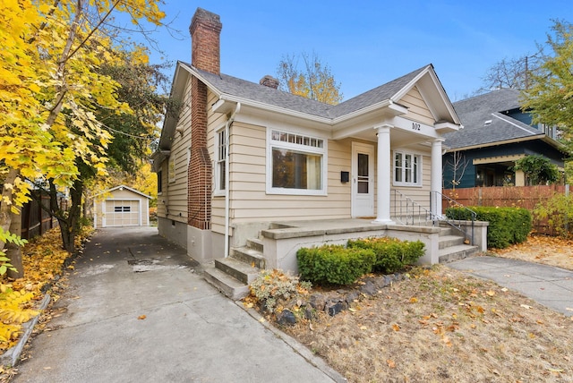 view of front of property featuring a chimney, fence, a garage, an outdoor structure, and driveway