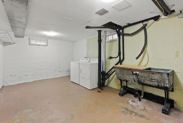 basement featuring washer and clothes dryer and a textured wall