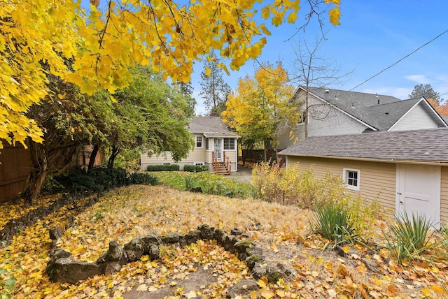 back of house featuring entry steps and a shingled roof