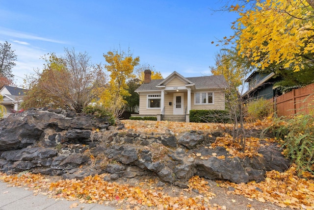 bungalow-style home with a chimney and fence