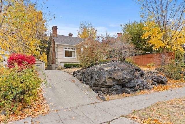 view of front of home featuring an outbuilding, a chimney, and fence